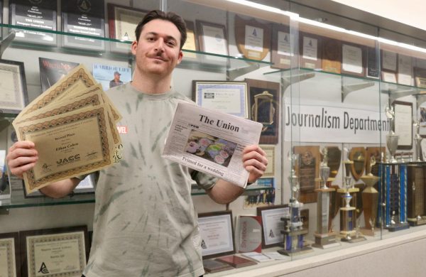 Former Union news editor and managing editor holds up the multiple certificate awards he received from the Journalism Association of Community Colleges on Nov. 14, for his work with the Union in past semesters while standing inside the Humanities Building which houses the student newsroom. (Delfino Camacho | The Union)