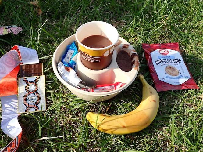 Detroit, Michigan, USA - April 15, 2023: hot chocolate themed picnic on grass. This is the finishers set for participants of Hot Chocolate Run. Includes banana, medal, hot chocolate mug and sweets.