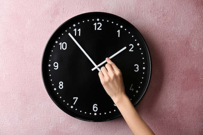 Woman changing time on big wall clock