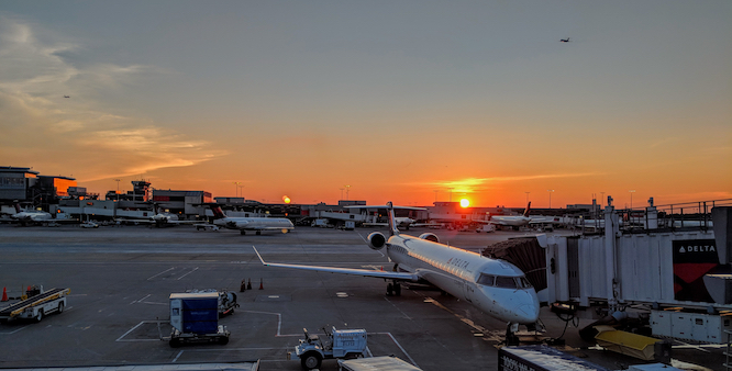 Atlanta, Georgia - August 11, 2018: Delta Regional Jet at gate with two planes taking off in background during sunset.