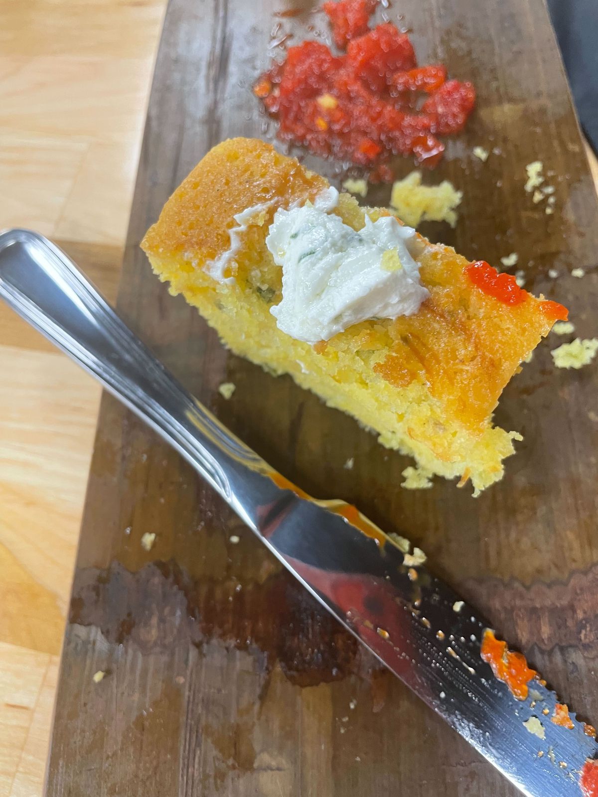 Single slice of loaf cornbread topped with whipped goat cheese on a wooden board